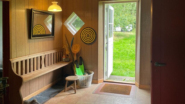 A wooden interior with a bench, a door leading outside, and two wall-mounted targets.