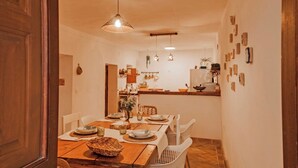 A dining area with a wooden table set for four, white chairs, and hanging pendant lights.
