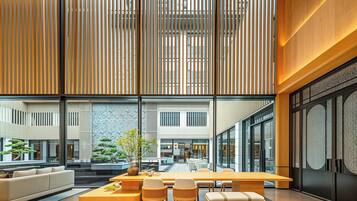 Un vestíbulo espacioso con diseño moderno, que incluye una recepción, zona de estar y amplios ventanales con vistas al interior del edificio.