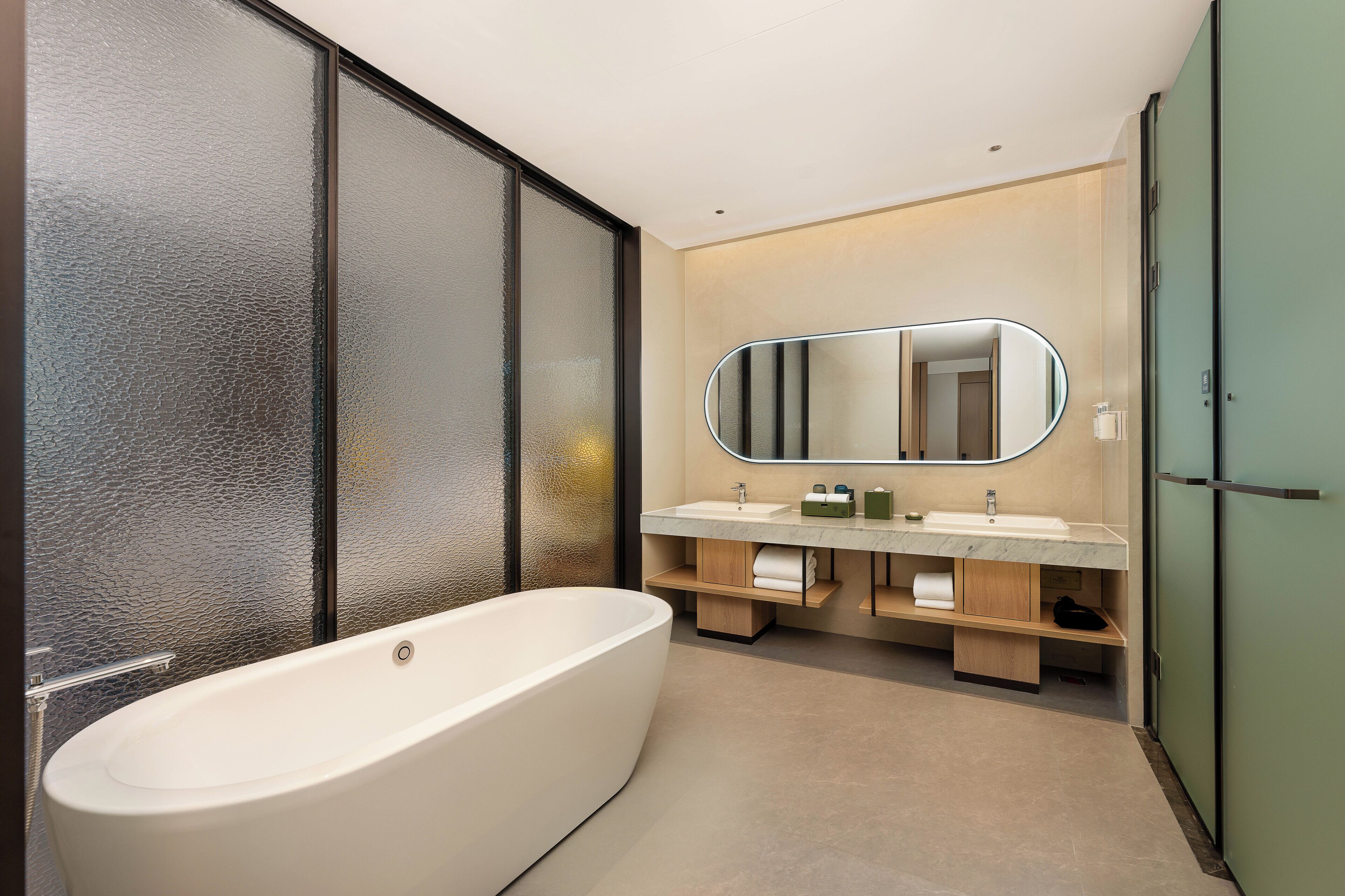 A modern bathroom with a freestanding bathtub, a large mirror, and a double sink vanity.