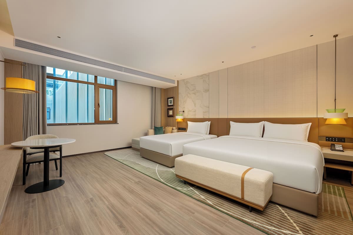 Una habitación de hotel con una cama grande, dos mesitas de noche, una pequeña mesa y una silla.