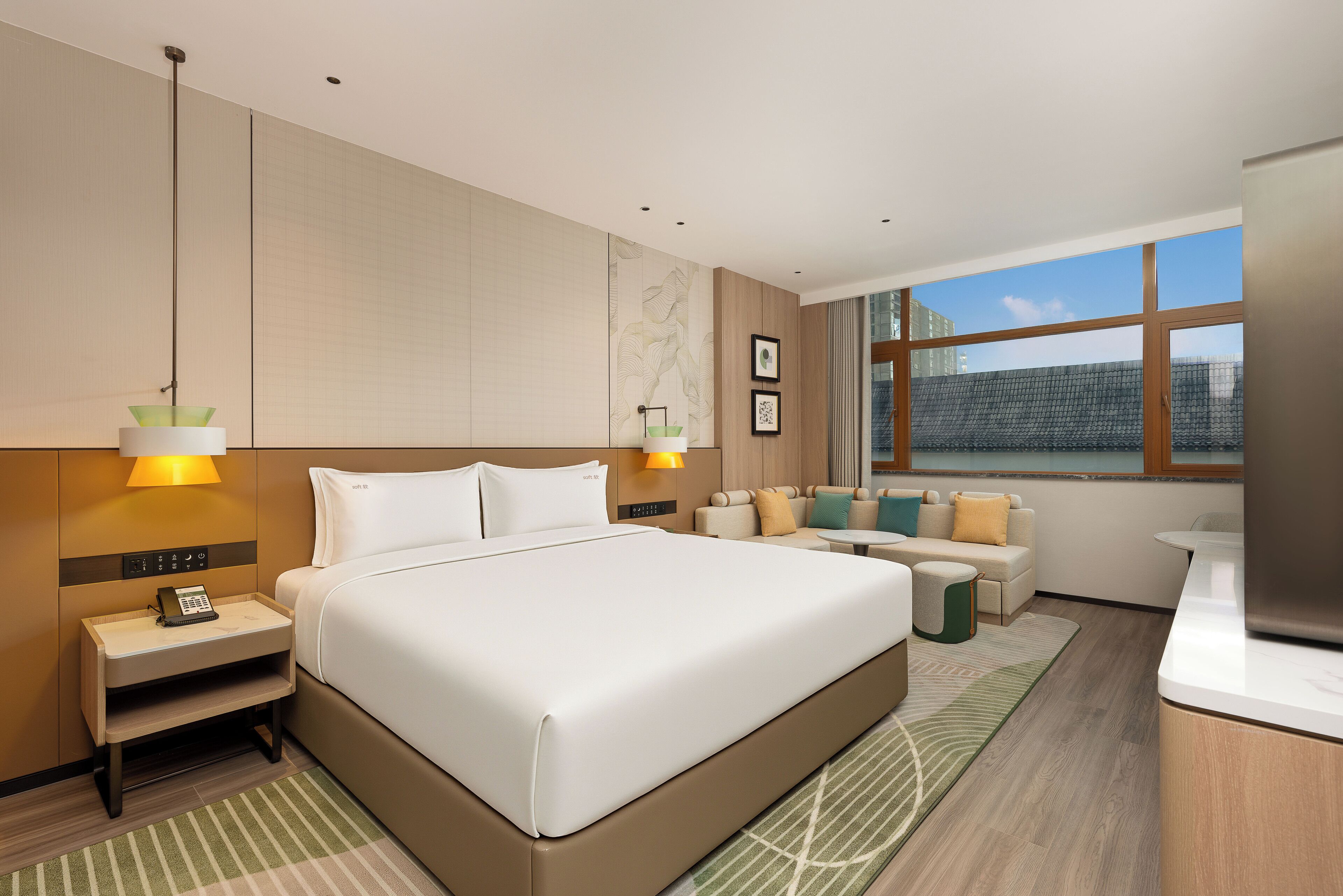 Habitación de hotel con una cama grande, un sofá, una mesita, un escritorio y una ventana con vistas a edificios.
