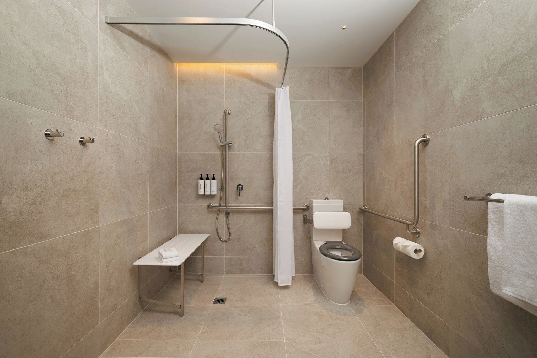 Een moderne badkamer met douche, toilet en bankje.