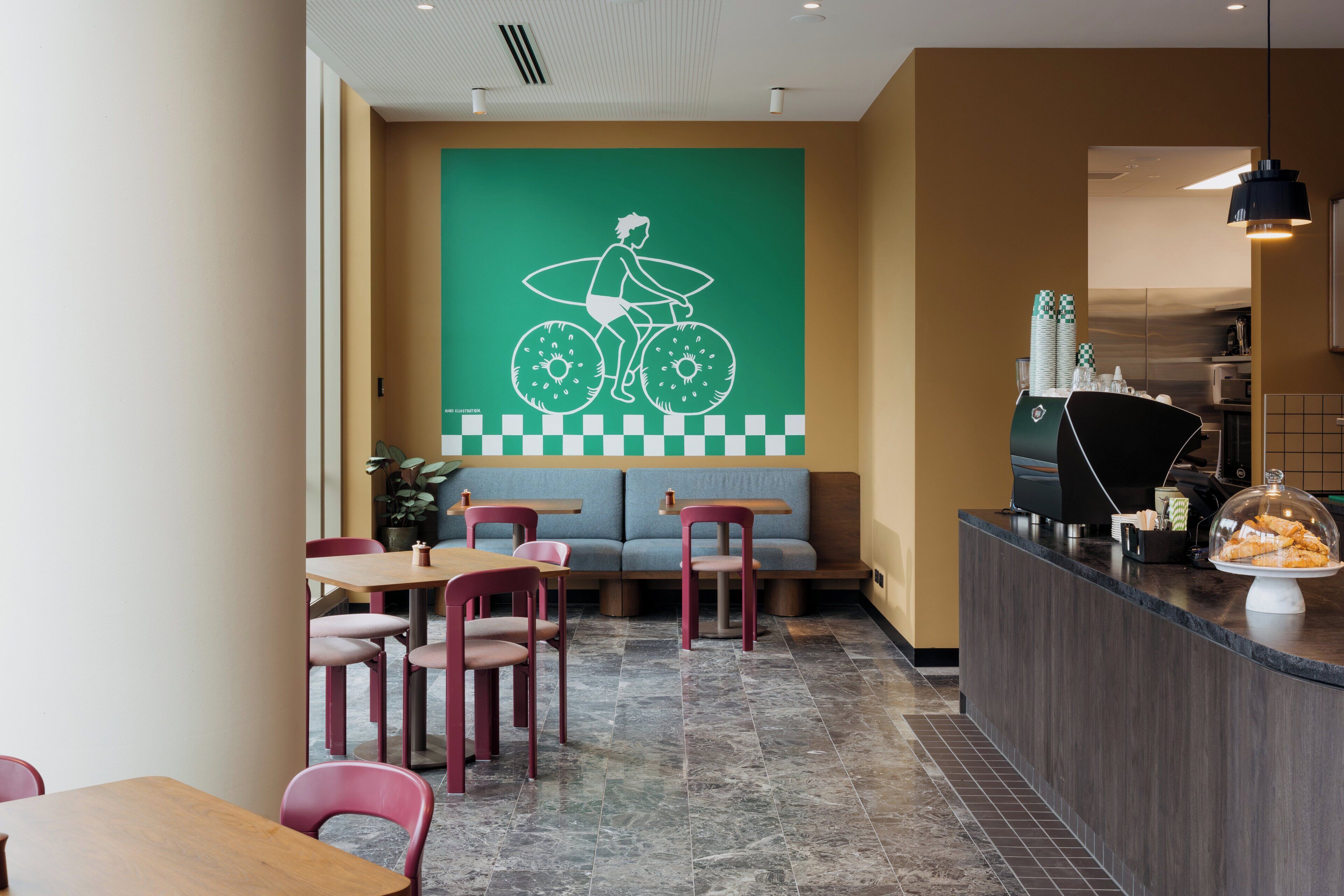 A restaurant with a counter, seating area, and a wall mural.