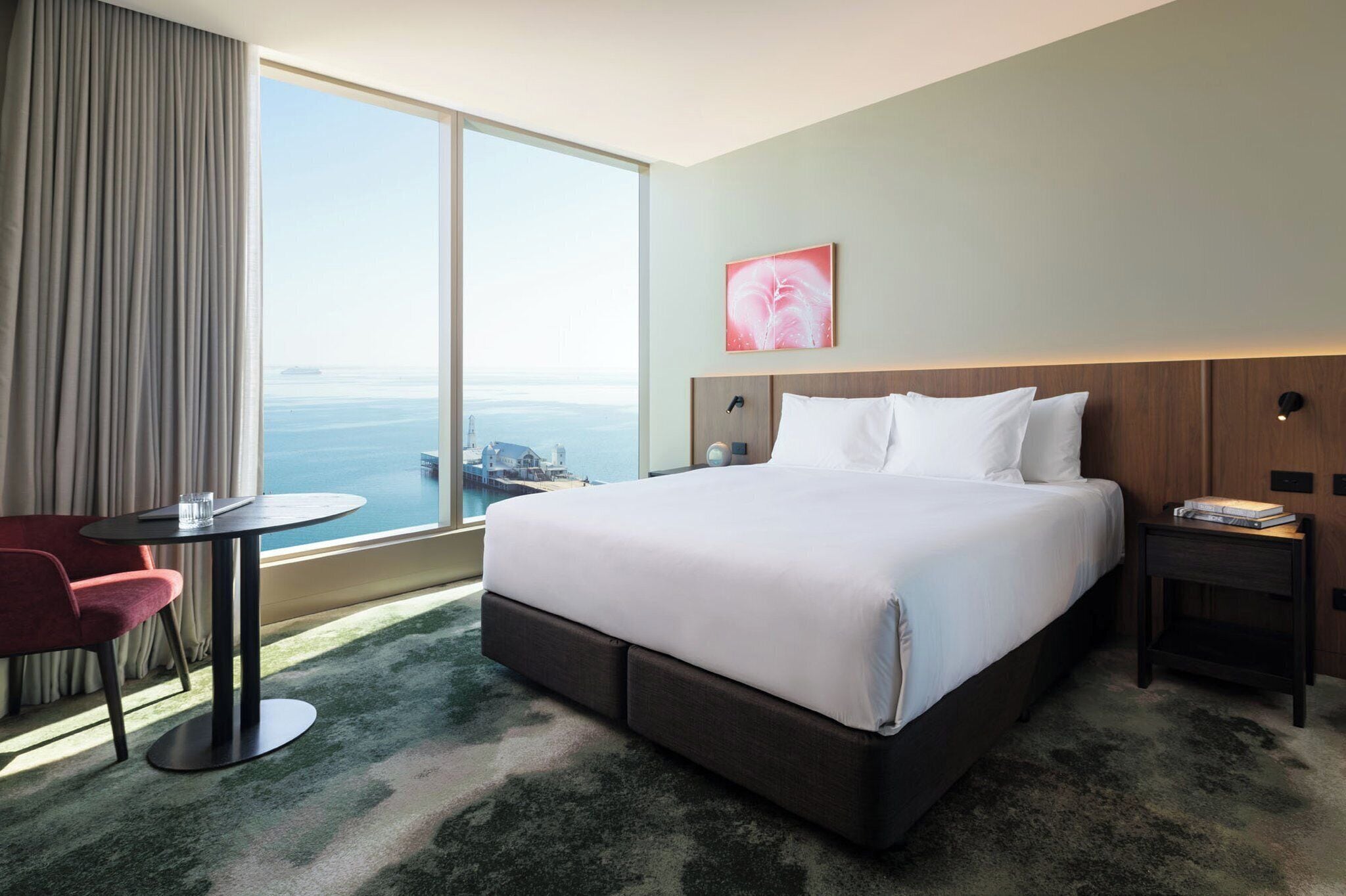 A hotel room with a large bed, a desk, a chair, and a view of the ocean.