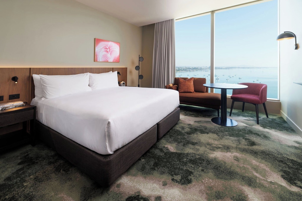 Habitación de hotel con una cama grande, una mesita, un sofá y vista al mar.
