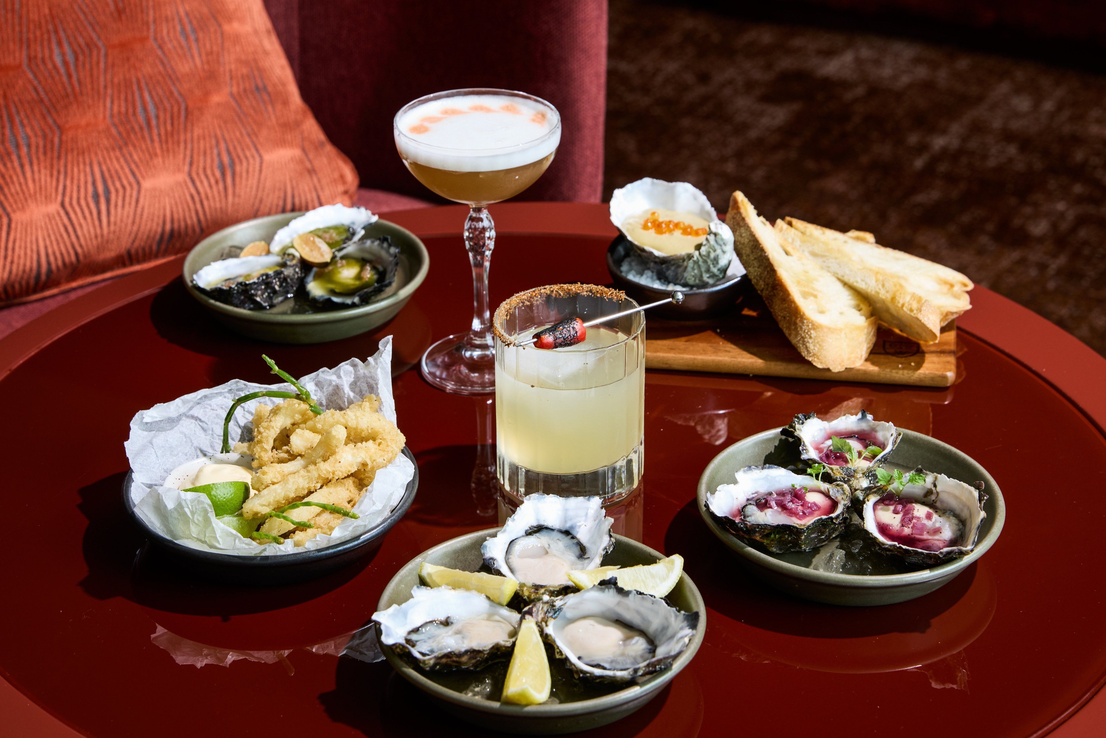 Una mesa con diversos platos de mariscos, un cóctel y pan.