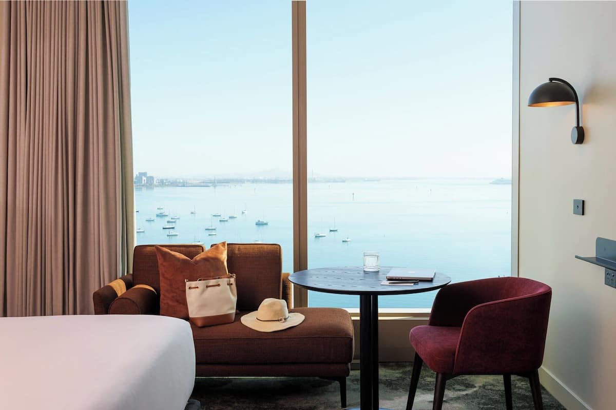Une chambre d’hôtel avec une grande fenêtre, un lit, un canapé, une table et une chaise.