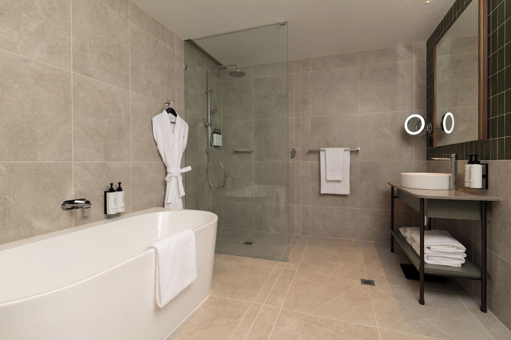 A modern bathroom with a bathtub, a glass-enclosed shower, and a vanity with a sink and mirror.
