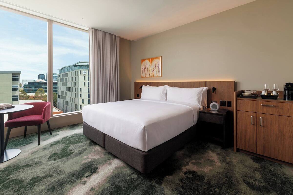 Une chambre d’hôtel avec un grand lit, un bureau, une chaise, une table de chevet et une armoire.