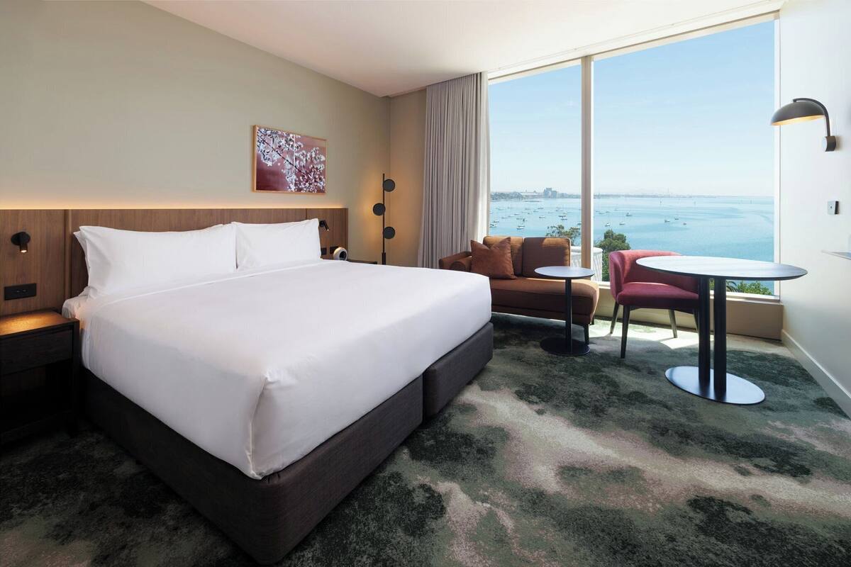 Une chambre d’hôtel avec un grand lit, un canapé, une petite table et une vue sur la mer.