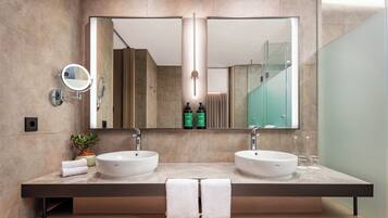 A modern bathroom with two sinks, a large mirror, and a towel rack.