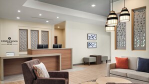 A hotel lobby with a reception desk, seating area, and decorative wall panels. - Candlewood Suites Mobile West I 65 by IHG (Mobile)