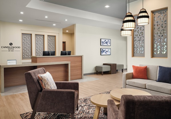 A hotel lobby with a reception desk, seating area, and decorative wall panels.