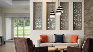 A modern living room with a sofa, chairs, a coffee table, and decorative panels. - Candlewood Suites Mobile West I 65 by IHG (Mobile)