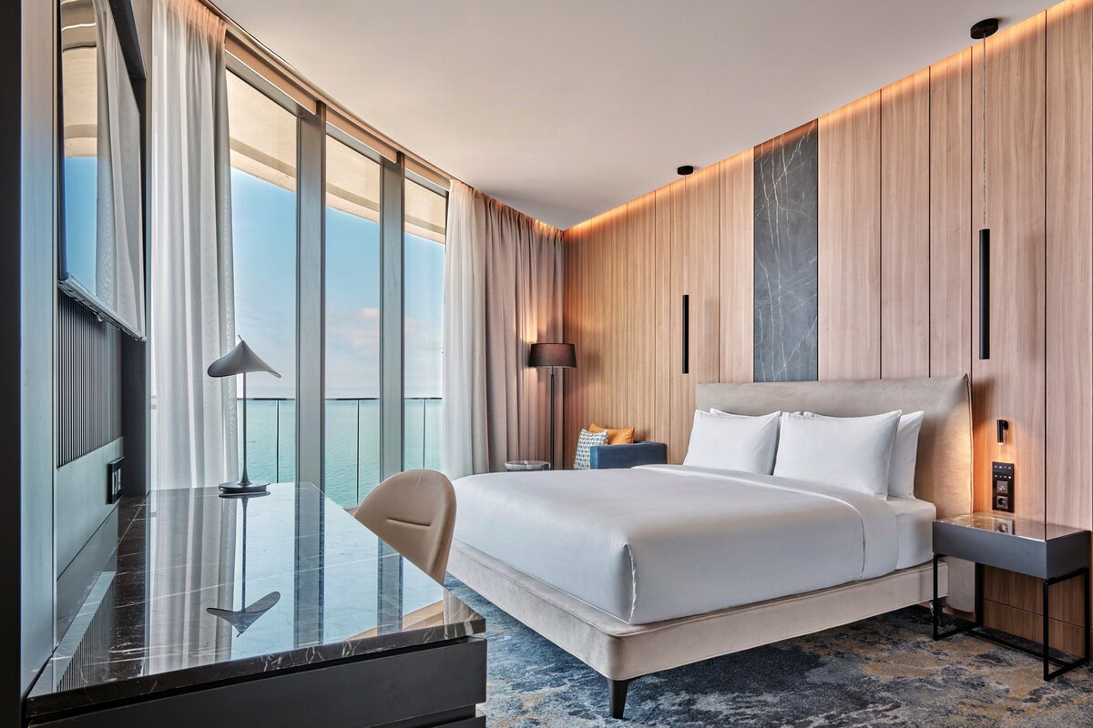 Une chambre d’hôtel moderne avec un grand lit, un bureau et une vue sur la mer.