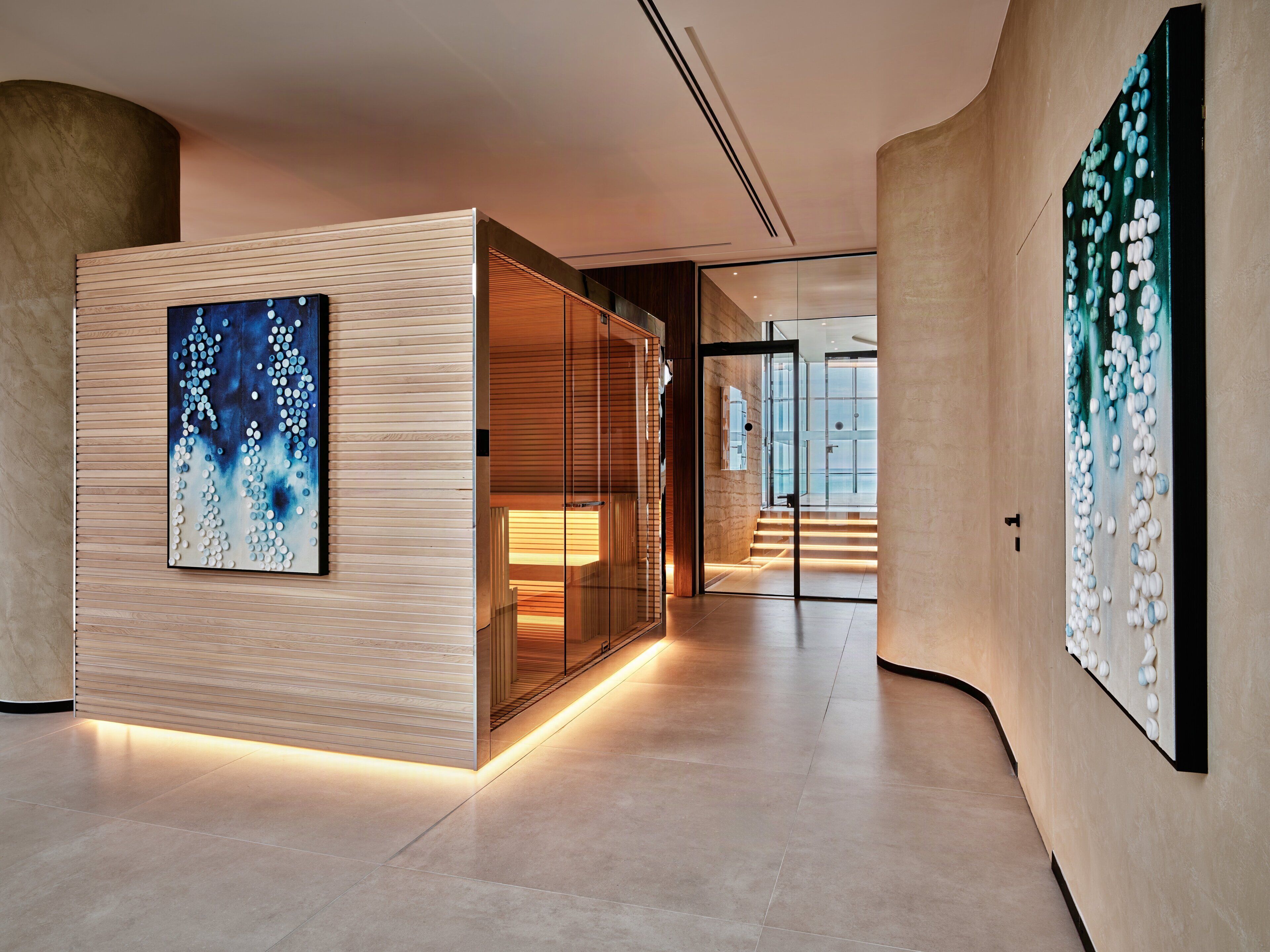 A modern interior with a wooden panel wall, a glass door leading to a staircase, and a large abstract painting.