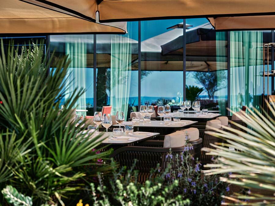 Un espacio de comedor al aire libre con mesas, sillas y sombrillas.
