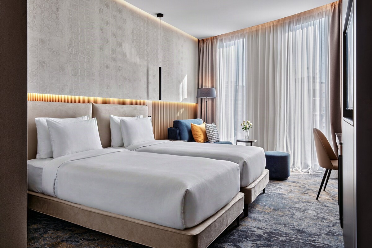 Une chambre d’hôtel moderne avec un grand lit, un petit canapé, un bureau et une chaise.