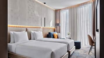 Una camera d'albergo moderna con un letto grande, un divano più piccolo, una scrivania e una sedia.