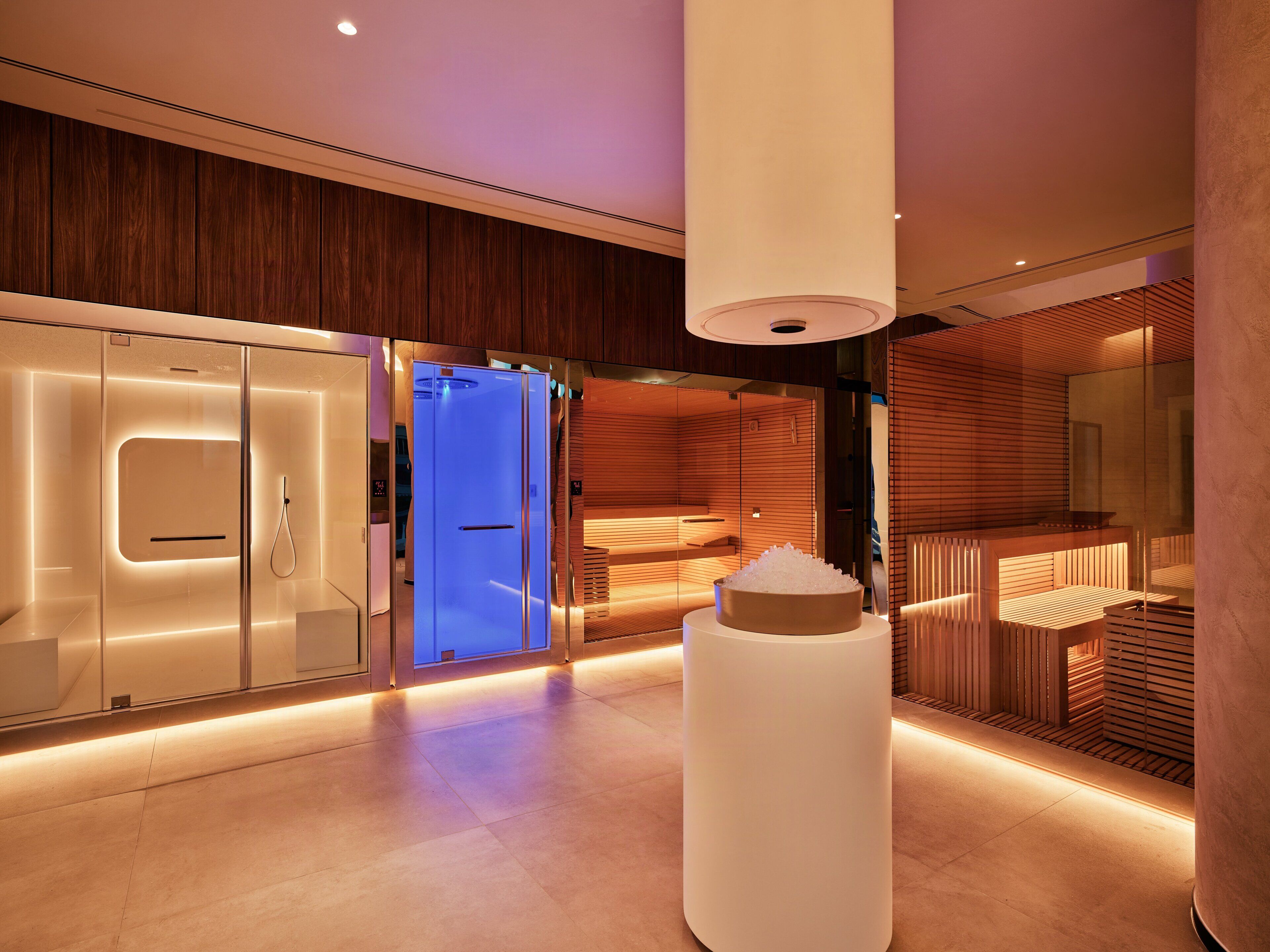 Un moderno vestíbulo de hotel con sauna, una zona de recepción y un gran pilar blanco.