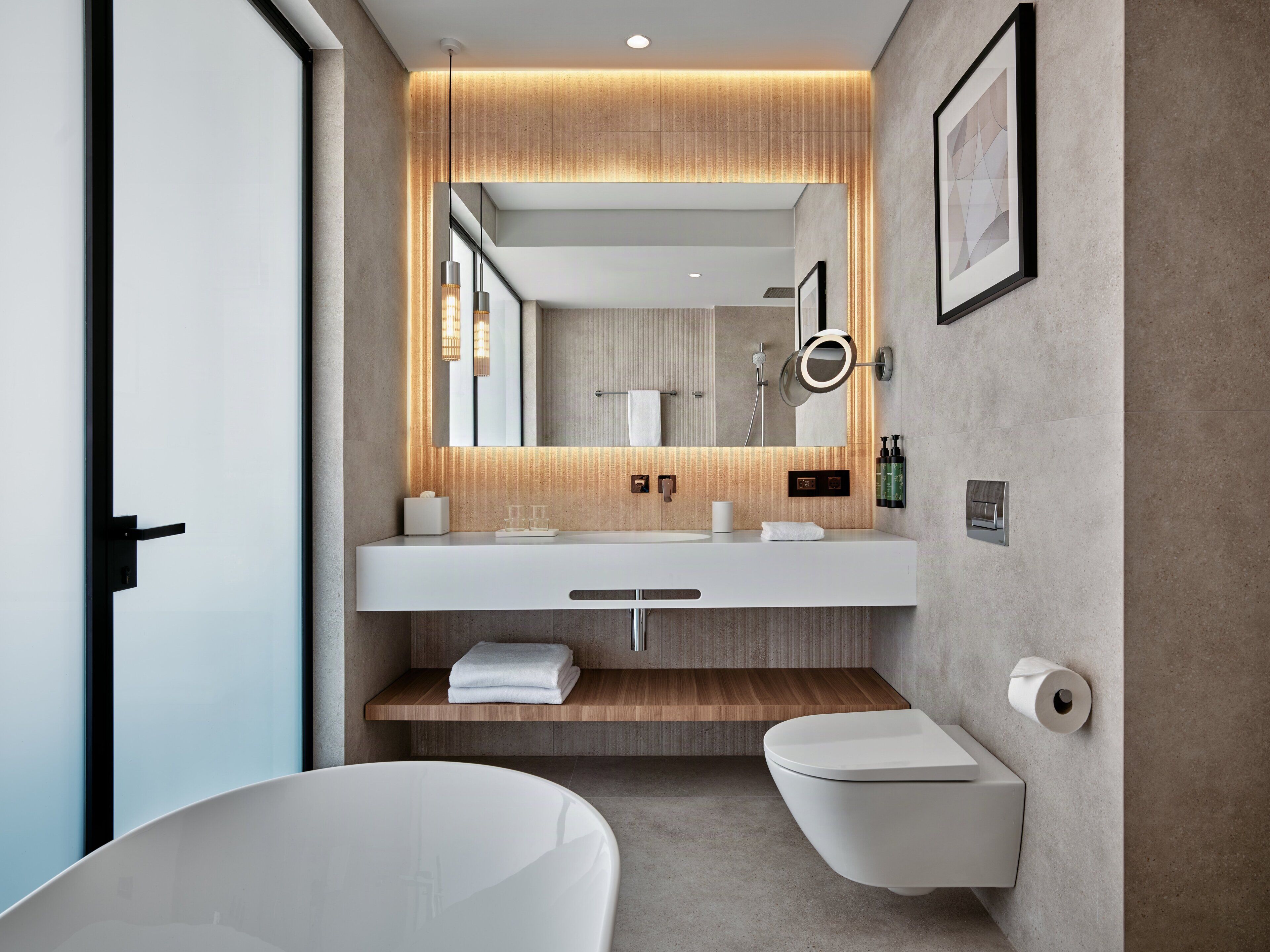 A modern bathroom with a large mirror, a white sink, a toilet, and a bathtub.