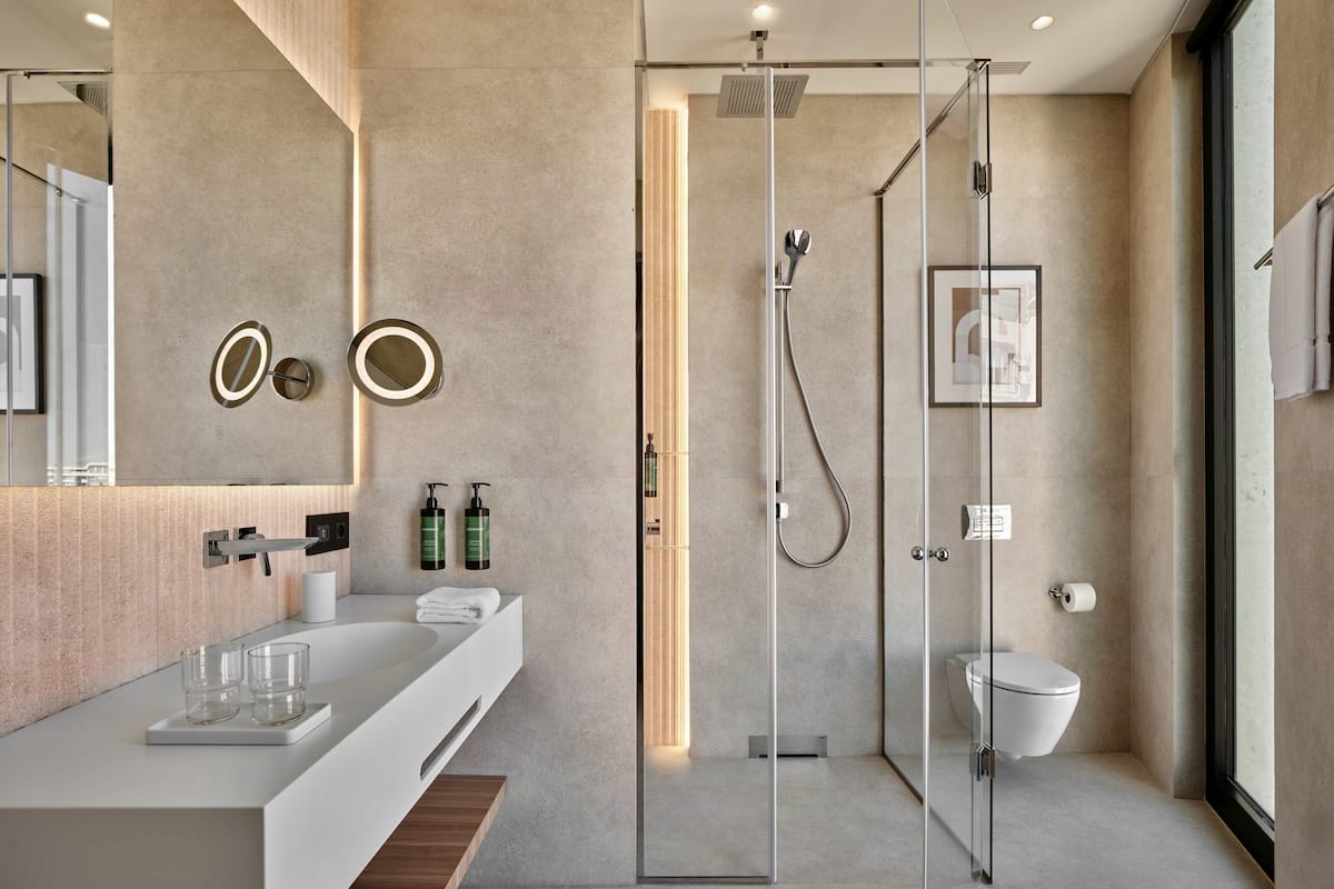 Une salle de bain moderne avec une douche à parois de verre, un lavabo blanc et un grand miroir.