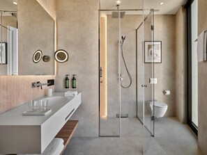 Une salle de bain moderne avec une douche à parois de verre, un lavabo blanc et un grand miroir.