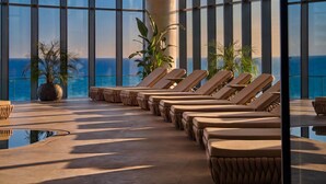 Un salon lumineux, doté de grandes fenêtres, d’une piscine et de plantes en pot.