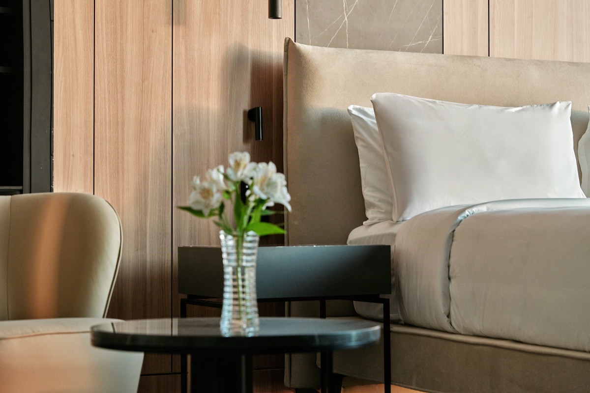 A modern room with a sofa, a small table with a vase of flowers, and wooden paneling on the walls.