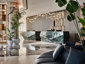 Un hall d’entrée moderne avec un comptoir d’accueil, un espace salon et de grandes plantes en pot.
