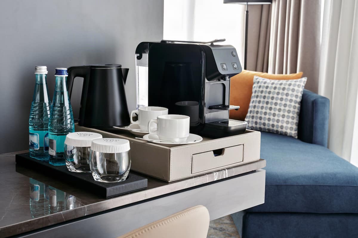 Une chambre d’hôtel équipée d’une machine à café, de bouteilles d’eau, de verres et d’un canapé.