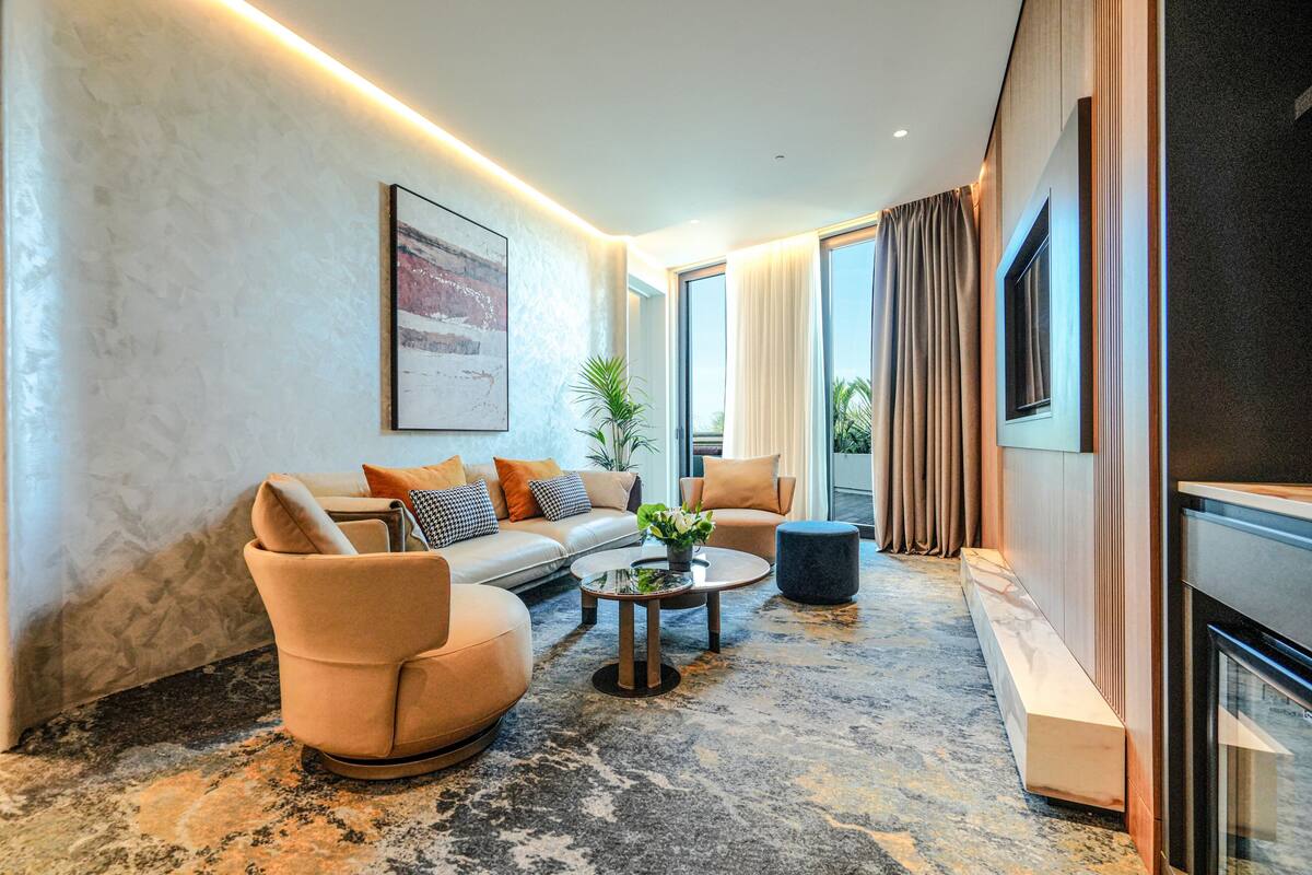 Een moderne woonkamer met een bank, fauteuils, een salontafel en een open haard.