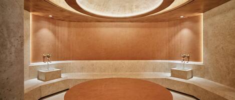 A circular room with a central round table, two sinks, and a recessed ceiling.