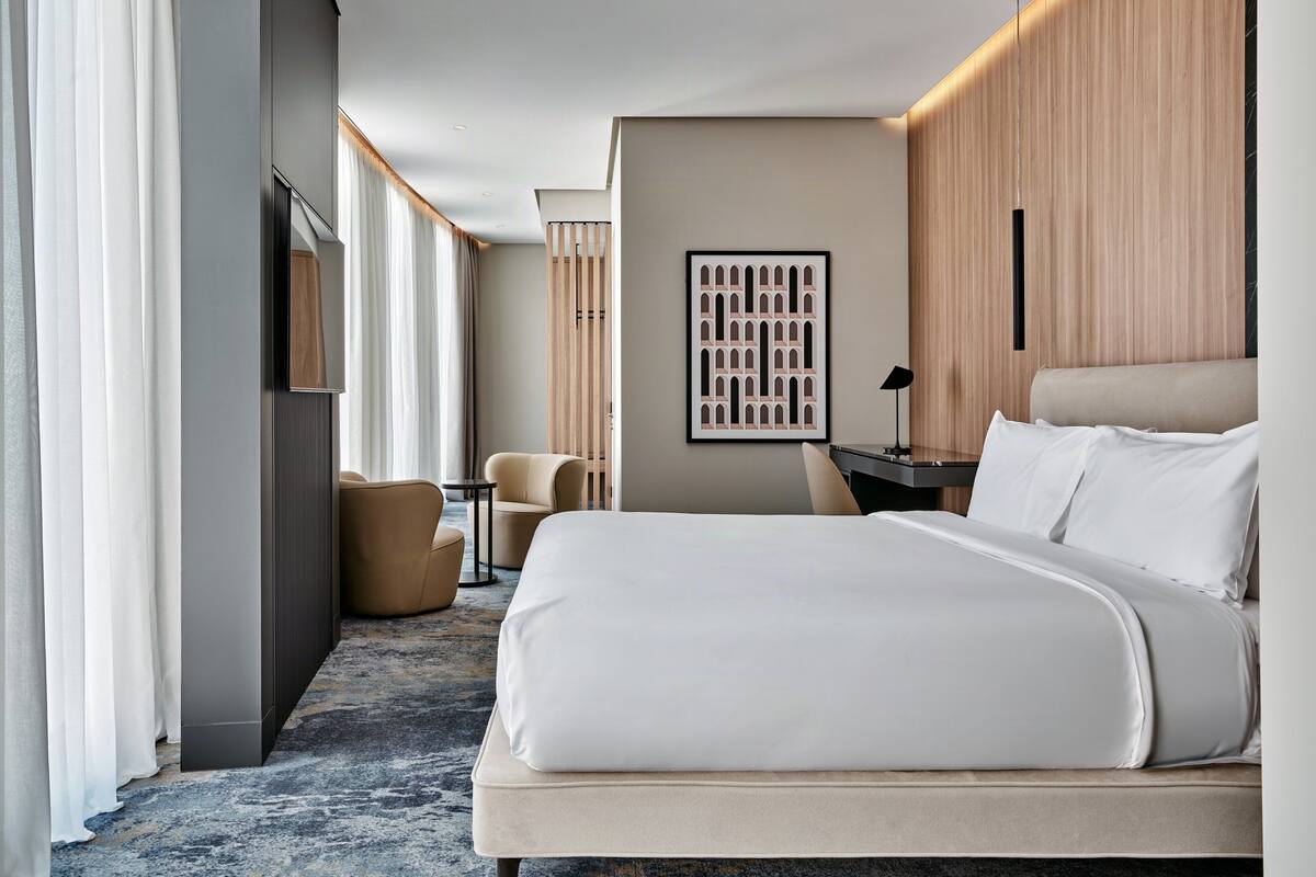 Een moderne hotelkamer met een groot bed, een bureau, een stoel en uitzicht op de stad.