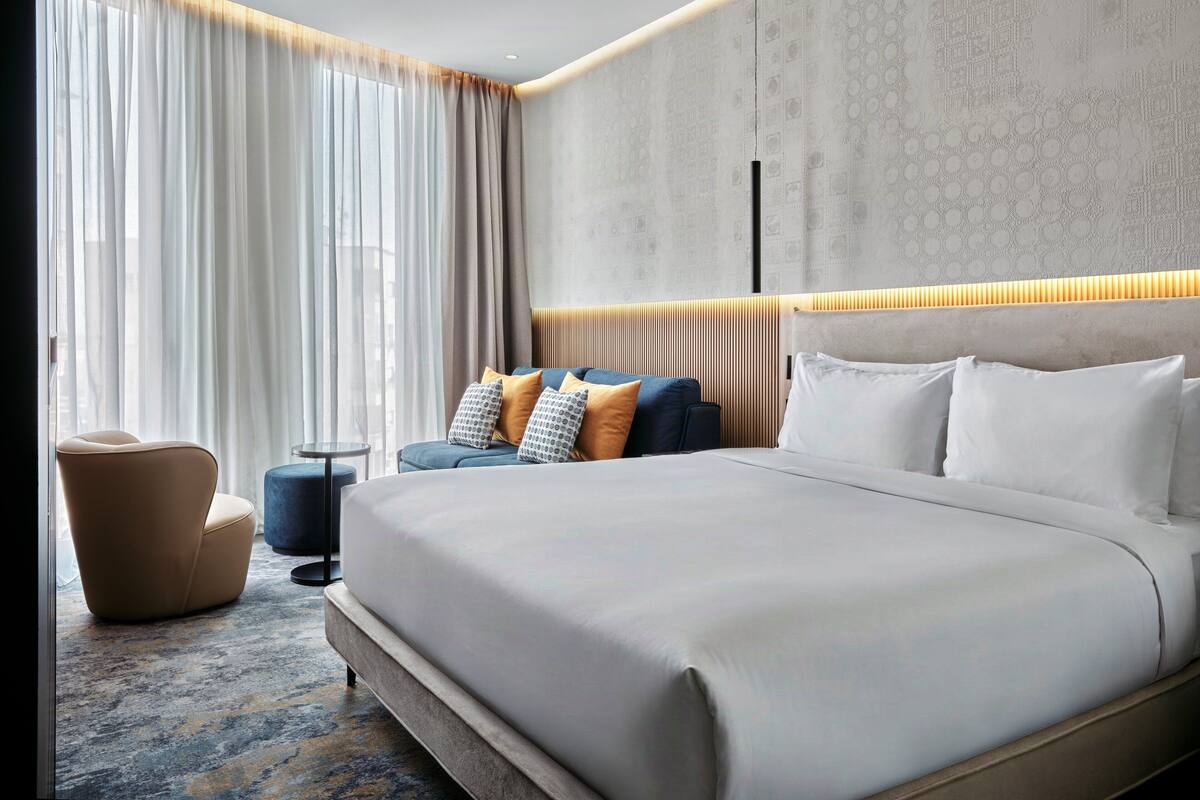 Een moderne hotelkamer met een groot bed, een sofa, een stoel en een kleine tafel.