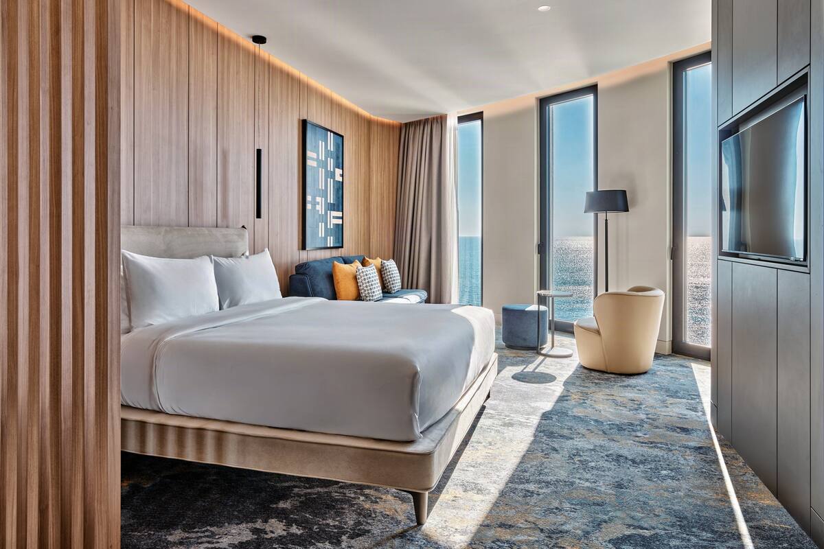 Een moderne hotelkamer met een groot bed, een zithoek en uitzicht op de oceaan.