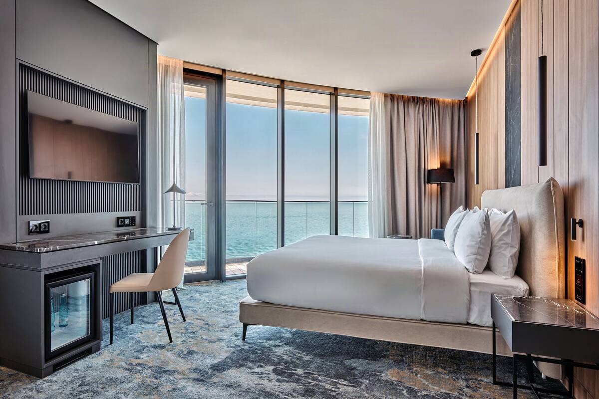 Ein modernes Hotelzimmer mit einem großen Bett, einem Schreibtisch und Meerblick.