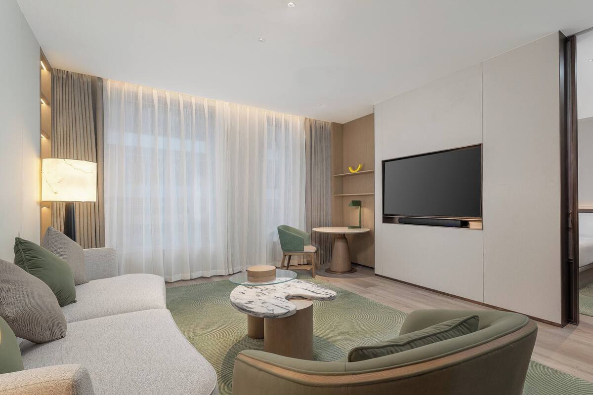 Habitación de hotel moderna con sofá, una mesita, televisor y espejo.
