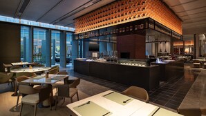 Een modern restaurant met een bar, grote ramen en een metselwerk muur.