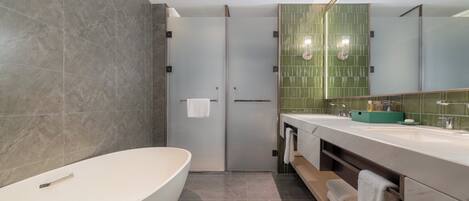 A modern bathroom with a freestanding bathtub, a vanity with a green sink, and a large mirror.