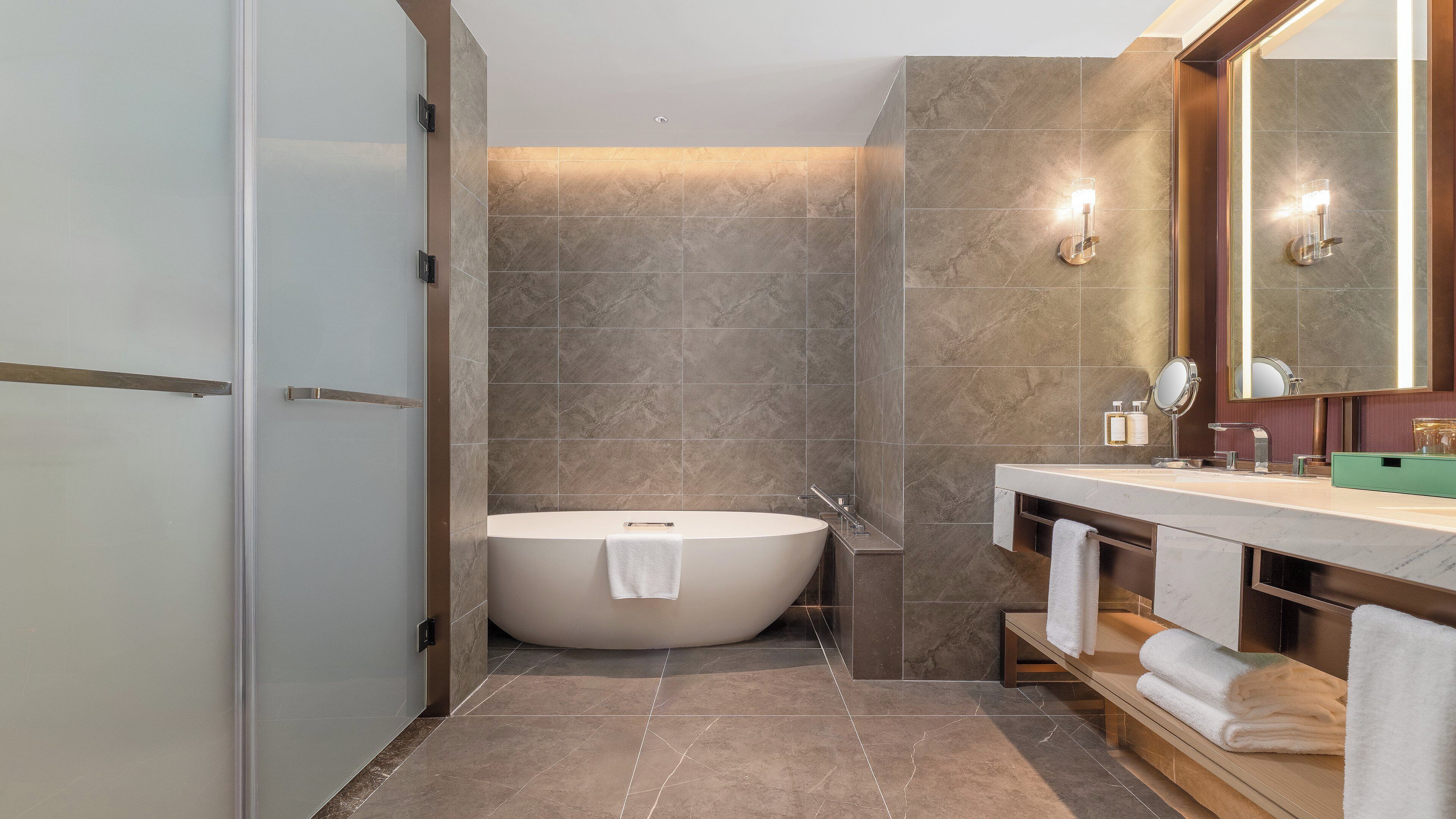 A modern bathroom with a freestanding bathtub, a vanity with a mirror, and a towel rack.
