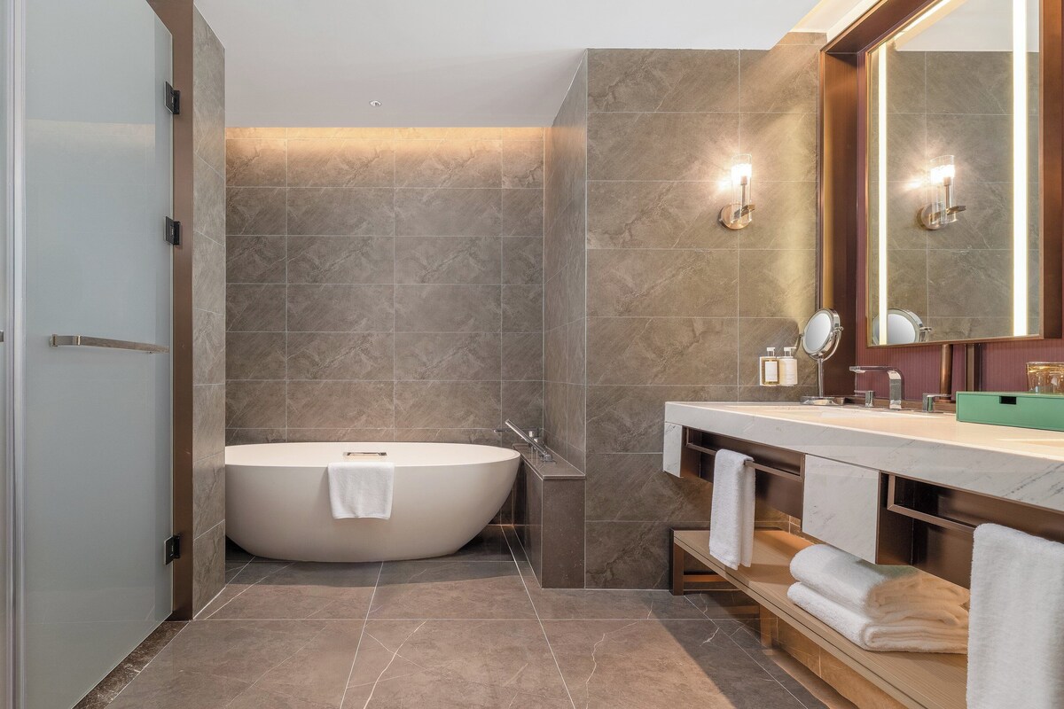 Un baño moderno con una bañera independiente, un tocador con espejo y un perchero para toallas.