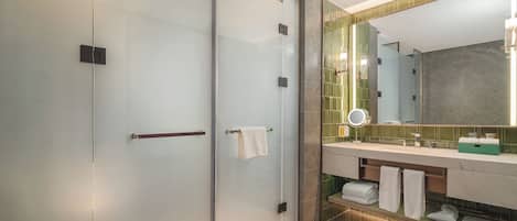 Une salle de bain moderne avec une douche à parois de verre, un meuble-lavabo avec miroir et un mur recouvert de carreaux.