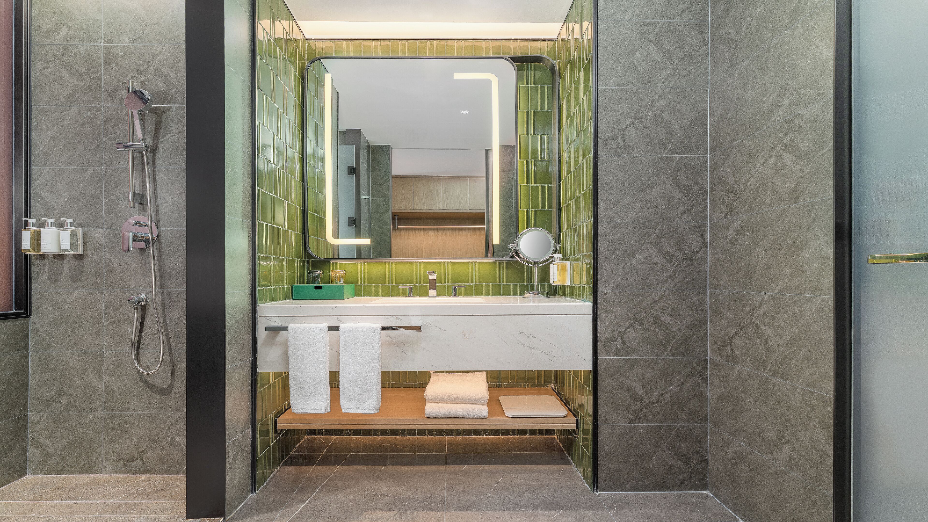 Un baño moderno con ducha, lavamanos con espejo y un perchero para toallas.
