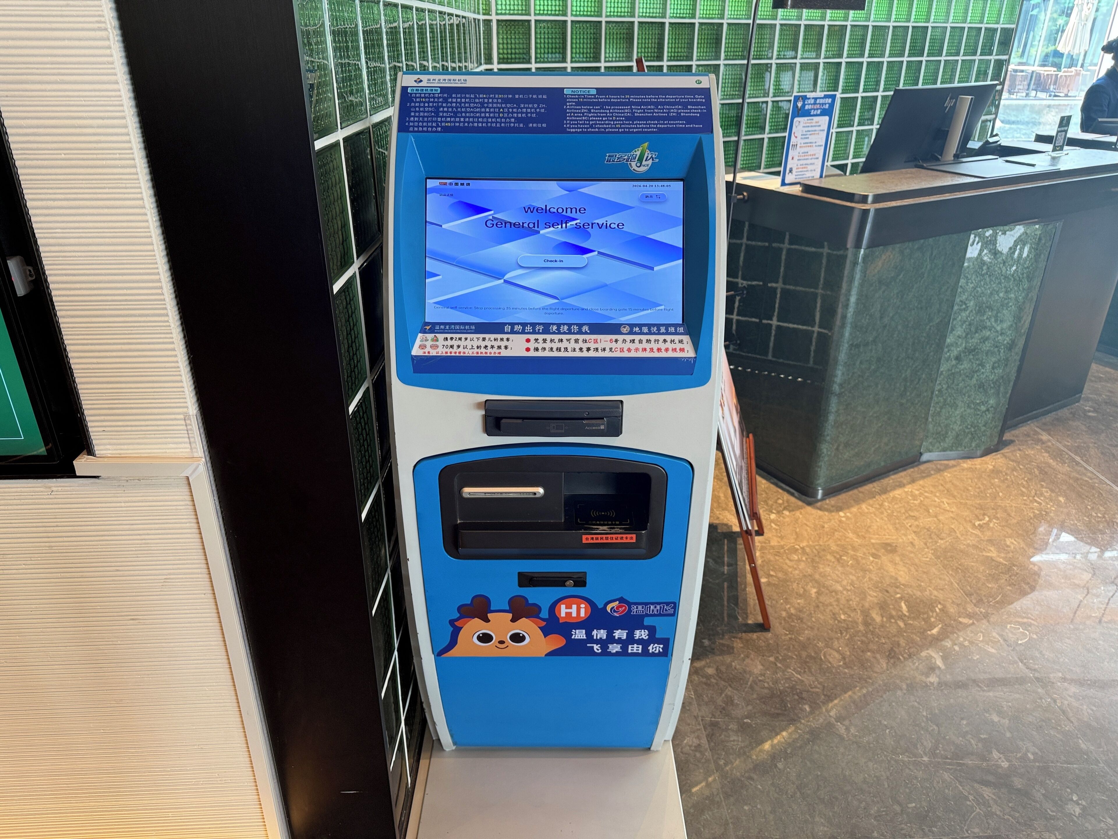 A self-service kiosk with a screen displaying 'Welcome General Self-Service' and a 'Check In' button.