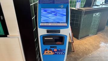 A self-service kiosk with a screen displaying 'Welcome General Self-Service' and a 'Check In' button.