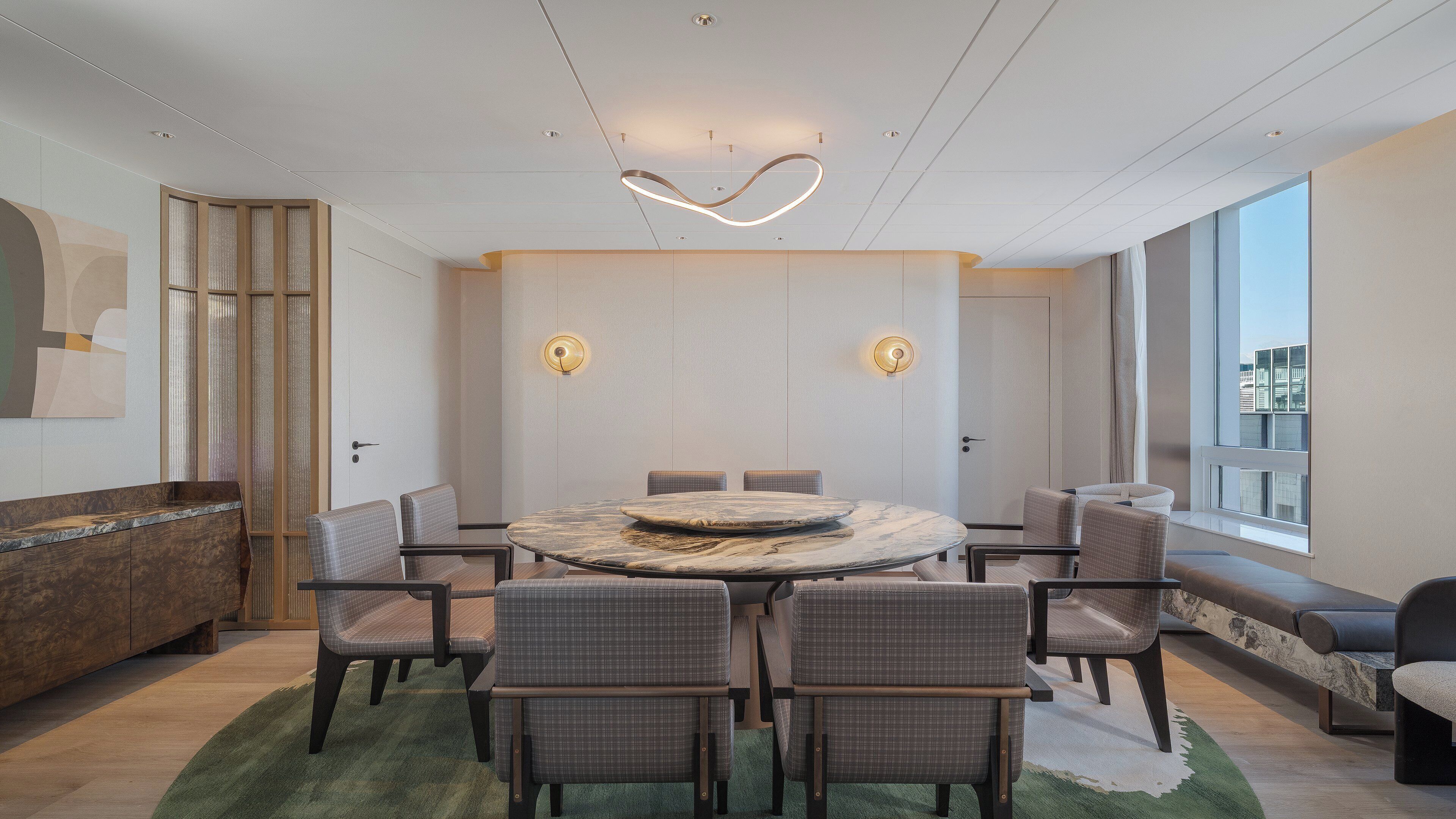 A modern conference room with a round table, six chairs, a marble centerpiece, and a large window.