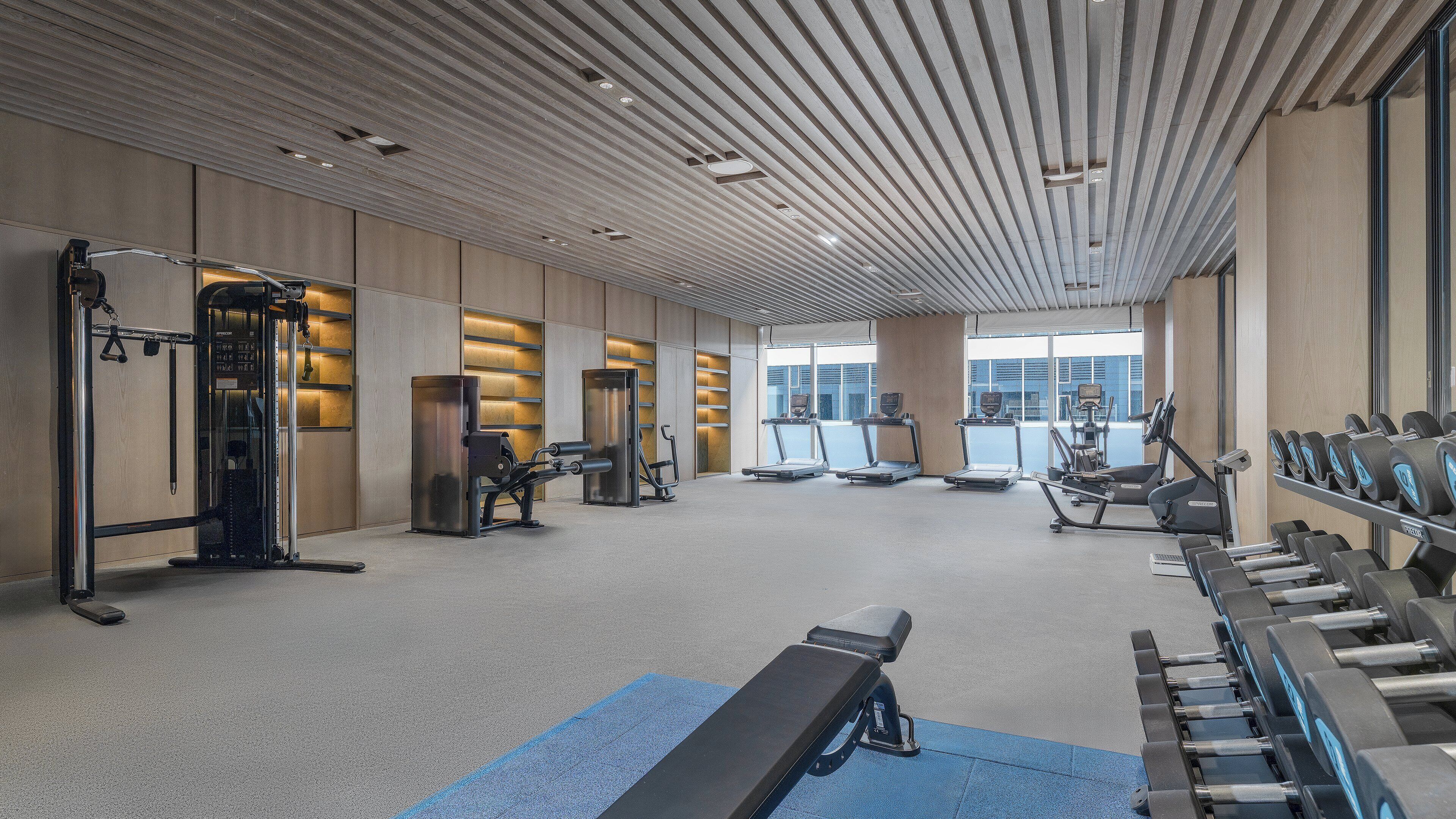 A modern gym with treadmills, elliptical machines, and free weights.