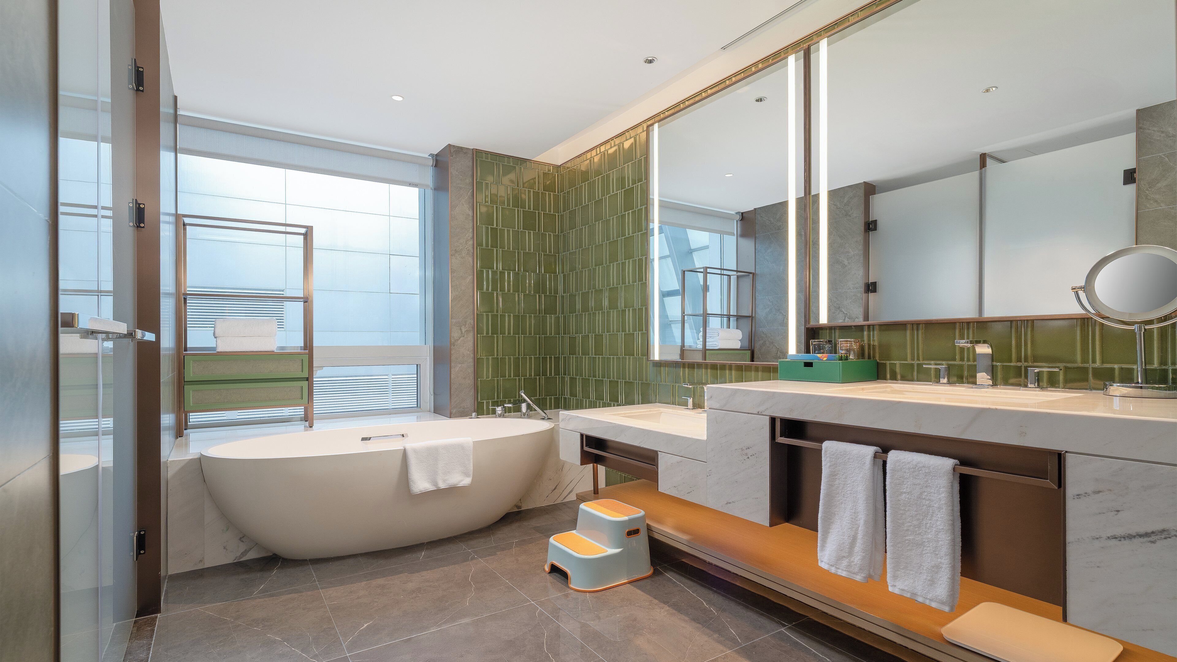 A modern bathroom with a freestanding bathtub, dual sinks, and a large mirror.